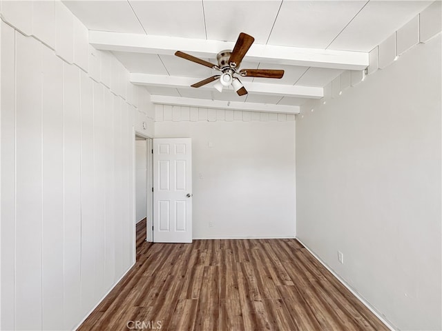 spare room featuring ceiling fan, vaulted ceiling with beams, dark hardwood / wood-style floors, and wood walls