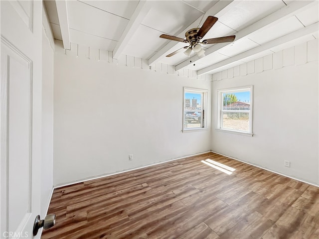 empty room with wood-type flooring, beamed ceiling, and ceiling fan