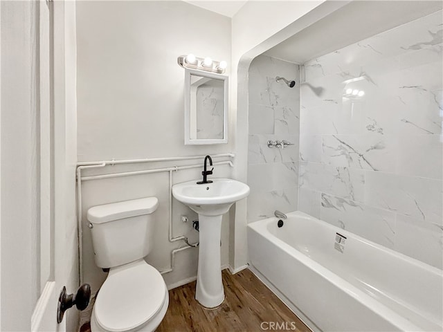 bathroom featuring tiled shower / bath, toilet, and wood-type flooring