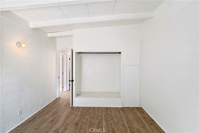 spare room featuring beamed ceiling and dark hardwood / wood-style floors