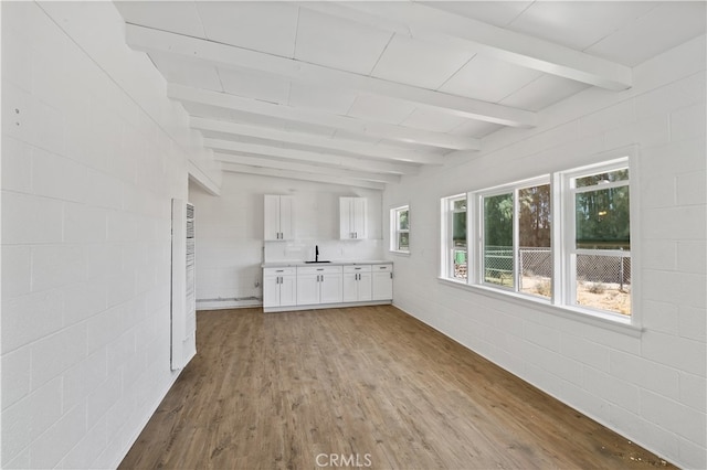 interior space featuring white cabinets, sink, light hardwood / wood-style flooring, and beam ceiling