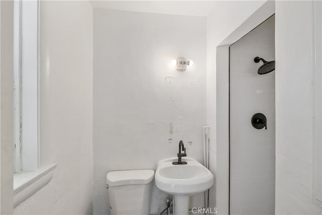 bathroom featuring toilet, sink, and a tile shower