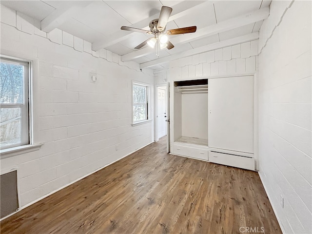 unfurnished bedroom featuring beam ceiling, hardwood / wood-style flooring, and multiple windows