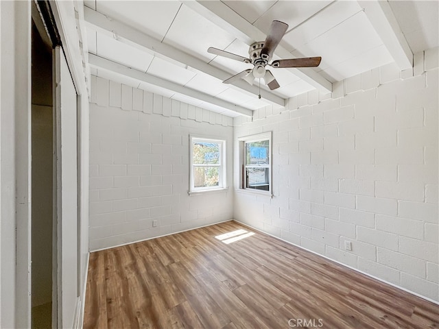 unfurnished room featuring beam ceiling, hardwood / wood-style flooring, and ceiling fan