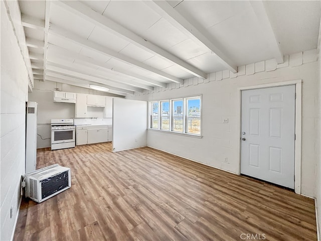 unfurnished living room with beamed ceiling and light wood-type flooring