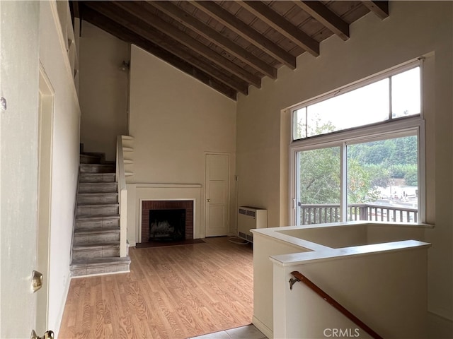 staircase with a brick fireplace, high vaulted ceiling, beamed ceiling, hardwood / wood-style flooring, and wooden ceiling