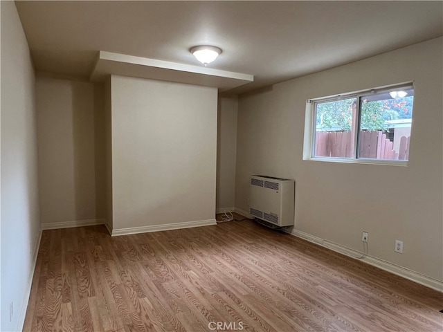 unfurnished room featuring heating unit and light wood-type flooring