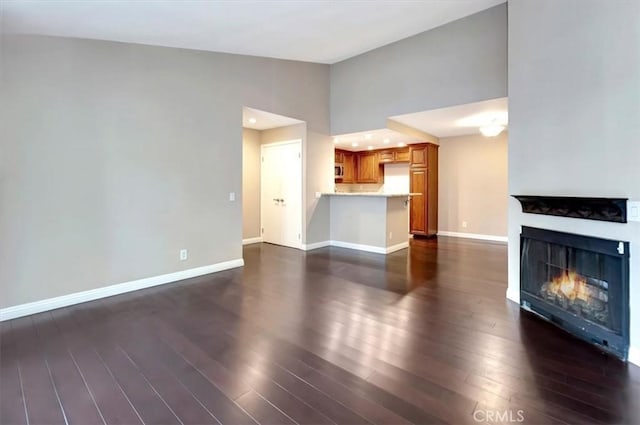 23556 Cambridge Rd Unit 327, Yorba Linda, CA 92887 - unfurnished living room with dark wood-style flooring, a warm lit fireplace, and baseboards