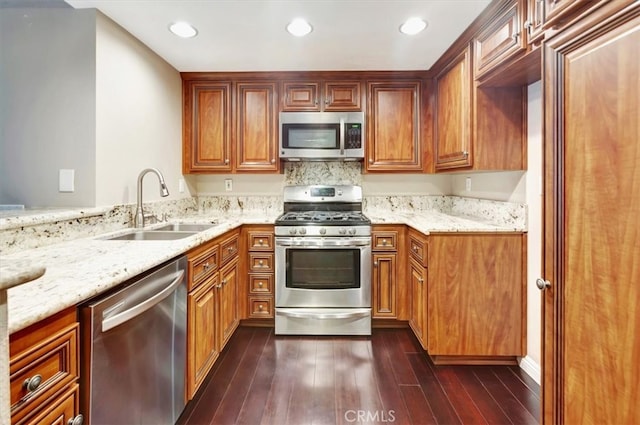 kitchen featuring sink, kitchen peninsula, appliances with stainless steel finishes, dark hardwood / wood-style floors, and light stone countertops