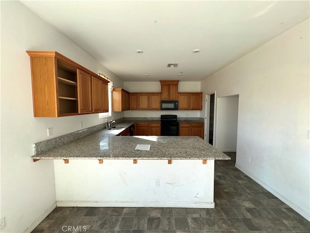 kitchen with sink, kitchen peninsula, black appliances, light stone countertops, and a kitchen bar