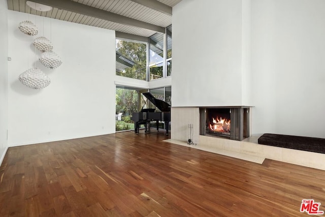 unfurnished living room featuring beamed ceiling, wood-type flooring, high vaulted ceiling, and wooden ceiling