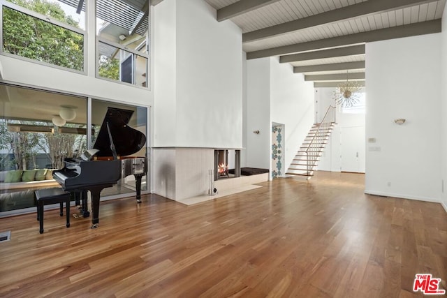 misc room with hardwood / wood-style flooring, a notable chandelier, beam ceiling, and a high ceiling