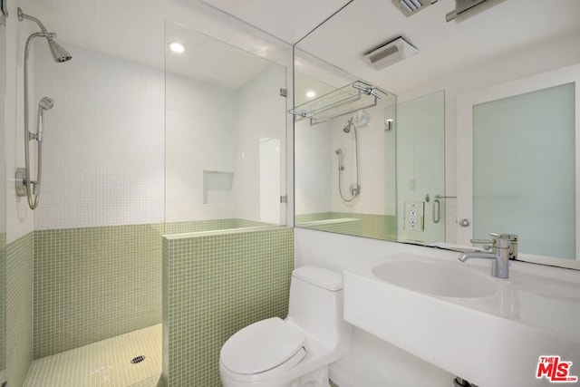 bathroom featuring an enclosed shower, sink, toilet, and tile walls