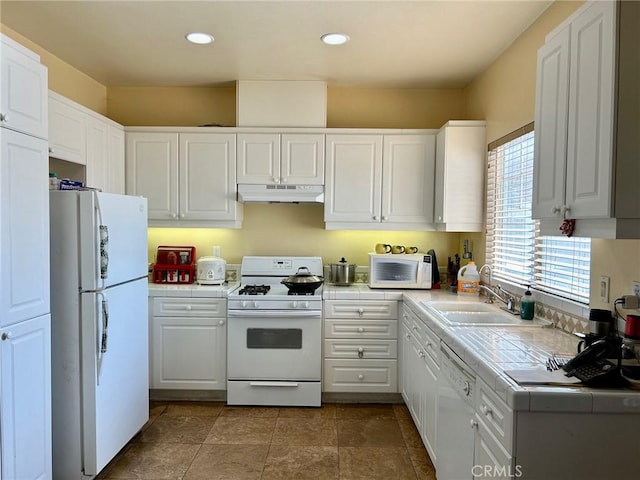 kitchen featuring tile counters, white cabinetry, sink, and white appliances