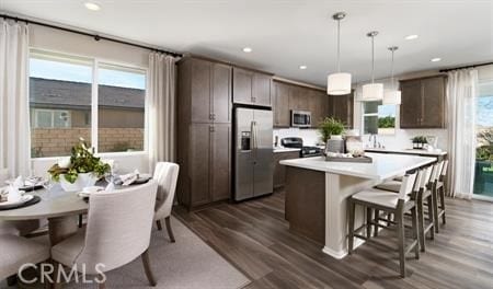 kitchen with dark brown cabinetry, a healthy amount of sunlight, hanging light fixtures, and stainless steel appliances