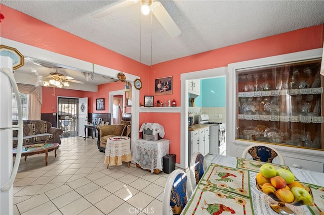 tiled dining space featuring a textured ceiling and ceiling fan