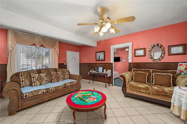 tiled living room featuring wood walls, a textured ceiling, and ceiling fan