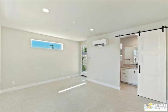 carpeted spare room with a barn door, a wall mounted air conditioner, and sink