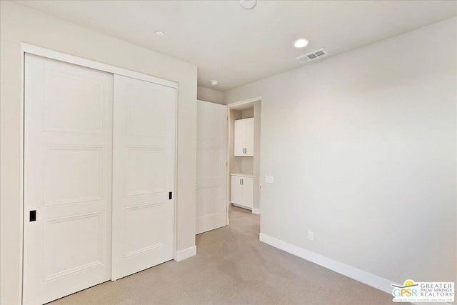 unfurnished bedroom with a closet and light colored carpet