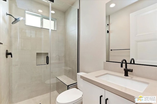 bathroom featuring vanity, a shower with shower door, and toilet