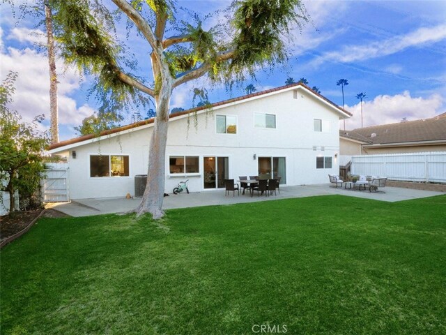 rear view of property with a patio and a lawn