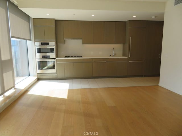 889 Francisco St Unit 1609, Los Angeles, CA 90017 - kitchen with gas stovetop, light countertops, a sink, light wood finished floors, and double oven