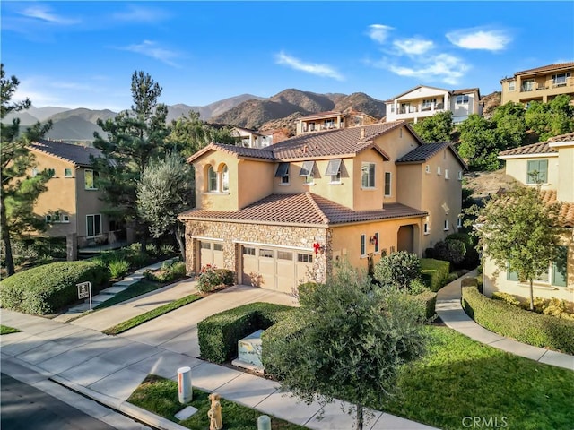 view of front of house featuring driveway, stone siding, a tiled roof, a mountain view, and stucco siding