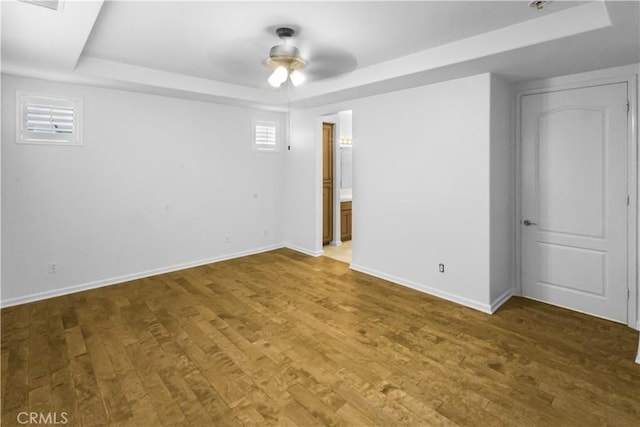 unfurnished bedroom featuring baseboards, a raised ceiling, and wood finished floors