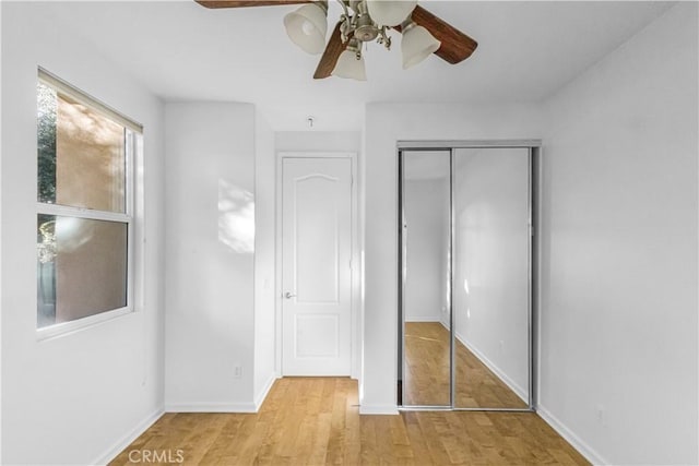 unfurnished bedroom with light wood-style floors, a ceiling fan, baseboards, and a closet