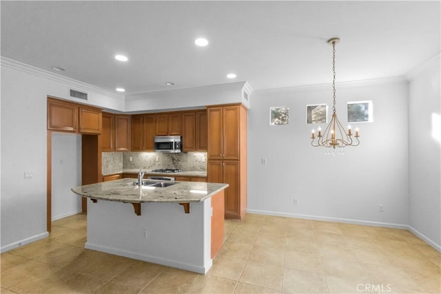 kitchen with brown cabinets, stainless steel microwave, a sink, and visible vents