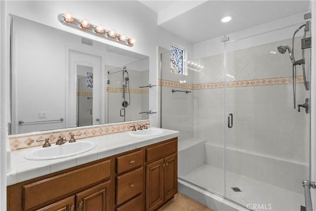 full bath featuring a stall shower, tile patterned flooring, a sink, and double vanity