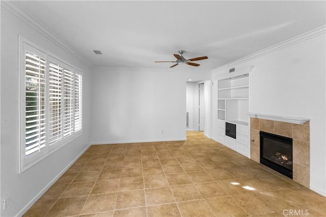 unfurnished living room featuring built in shelves, a fireplace, a ceiling fan, baseboards, and ornamental molding