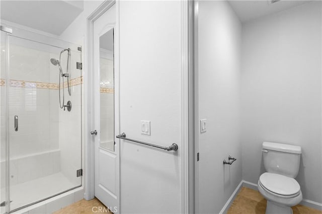 bathroom featuring a shower stall, toilet, and baseboards