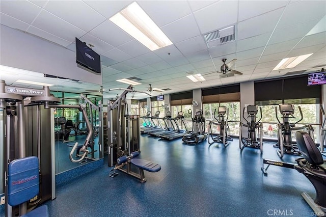 exercise room with ceiling fan, a paneled ceiling, and visible vents