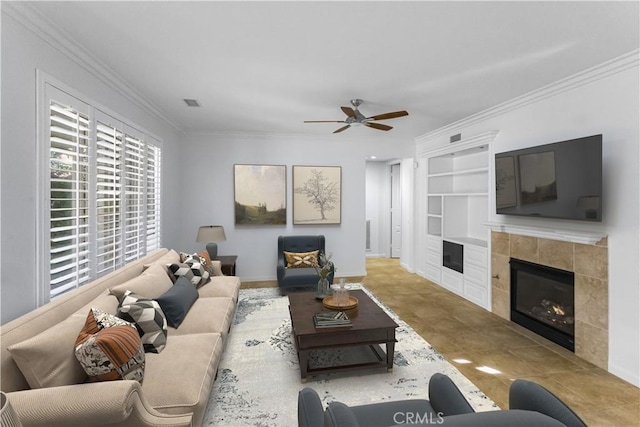 living area with visible vents, a ceiling fan, a tile fireplace, ornamental molding, and built in shelves