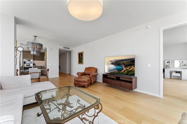 living room featuring light hardwood / wood-style flooring and an inviting chandelier