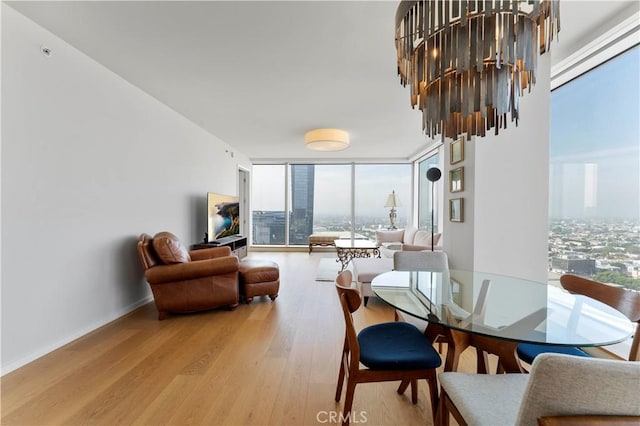 dining room with a notable chandelier, a wall of windows, and light wood-type flooring