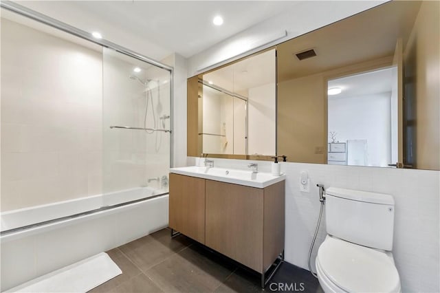 full bathroom featuring tile patterned flooring, vanity, bath / shower combo with glass door, and toilet