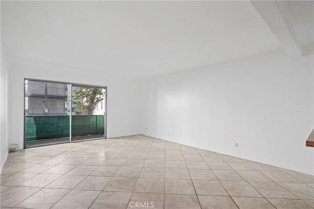 tiled empty room with beamed ceiling