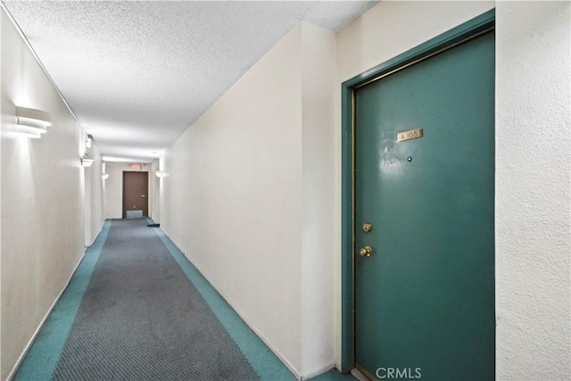 hall with a textured ceiling and carpet