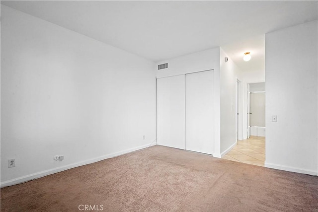 unfurnished bedroom featuring light carpet and a closet