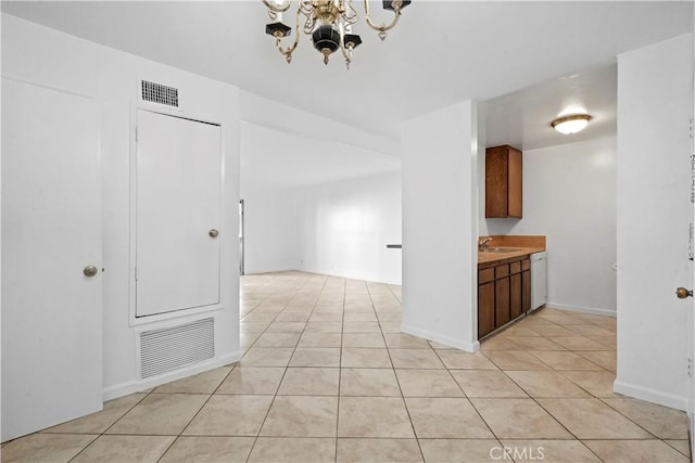 interior space with white dishwasher, sink, light tile patterned floors, and an inviting chandelier