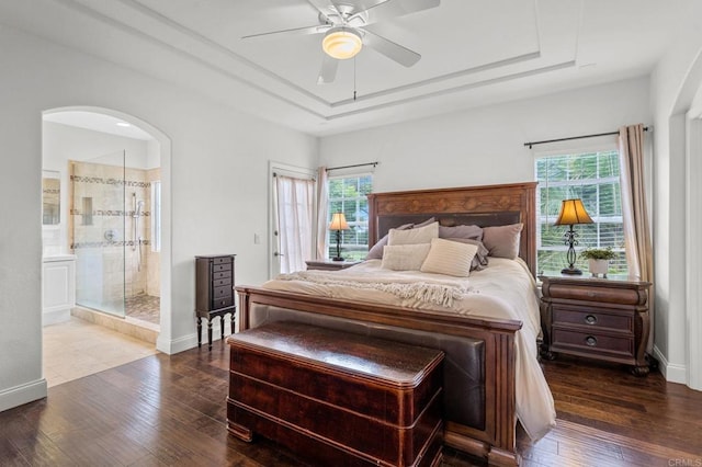 bedroom with a raised ceiling, wood-type flooring, and multiple windows