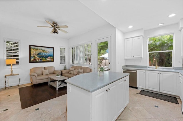 kitchen featuring stainless steel dishwasher, plenty of natural light, sink, and white cabinets