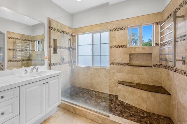 bathroom with vanity, a wealth of natural light, and a tile shower