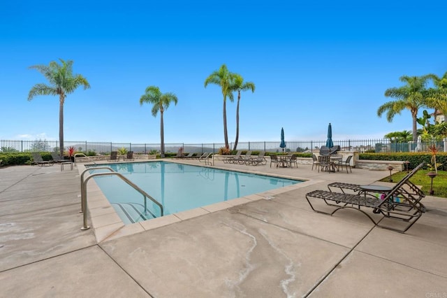 view of pool with a water view and a patio