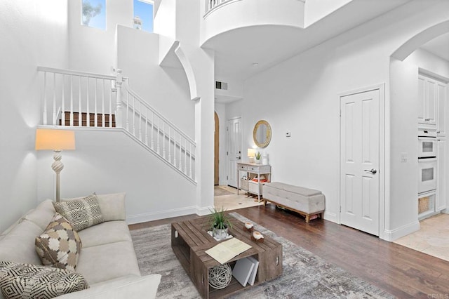 living room featuring wood-type flooring and a towering ceiling