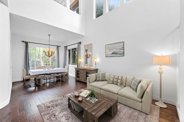 living room featuring an inviting chandelier, a towering ceiling, and dark hardwood / wood-style flooring