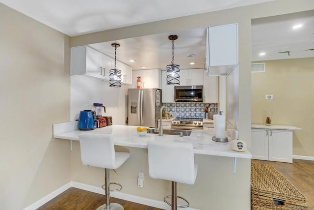 kitchen with stainless steel appliances, hanging light fixtures, dark hardwood / wood-style floors, and white cabinetry