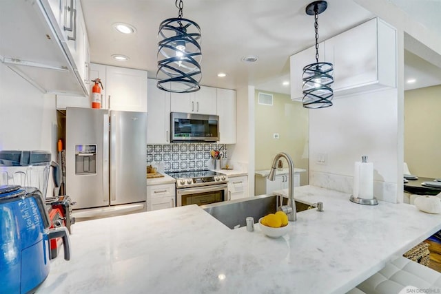 kitchen featuring stainless steel appliances, pendant lighting, white cabinets, and sink